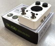 Mooer GL100 Groove Loop - begagnad En vit musikapparat med knappar och skärmfält, placerad ovanpå en svart och vit kartong med produktinformation. Kartongen har texten